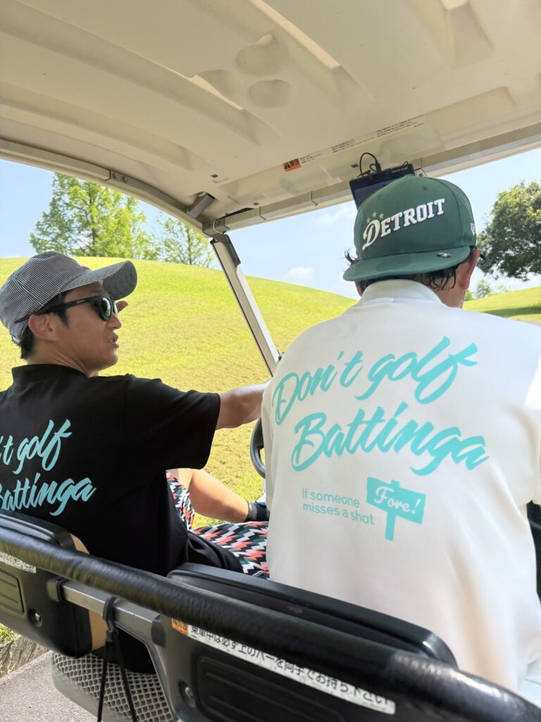 don'tgolf BATTINGAとバックプリントされたモックネックを着て談笑する男性２人